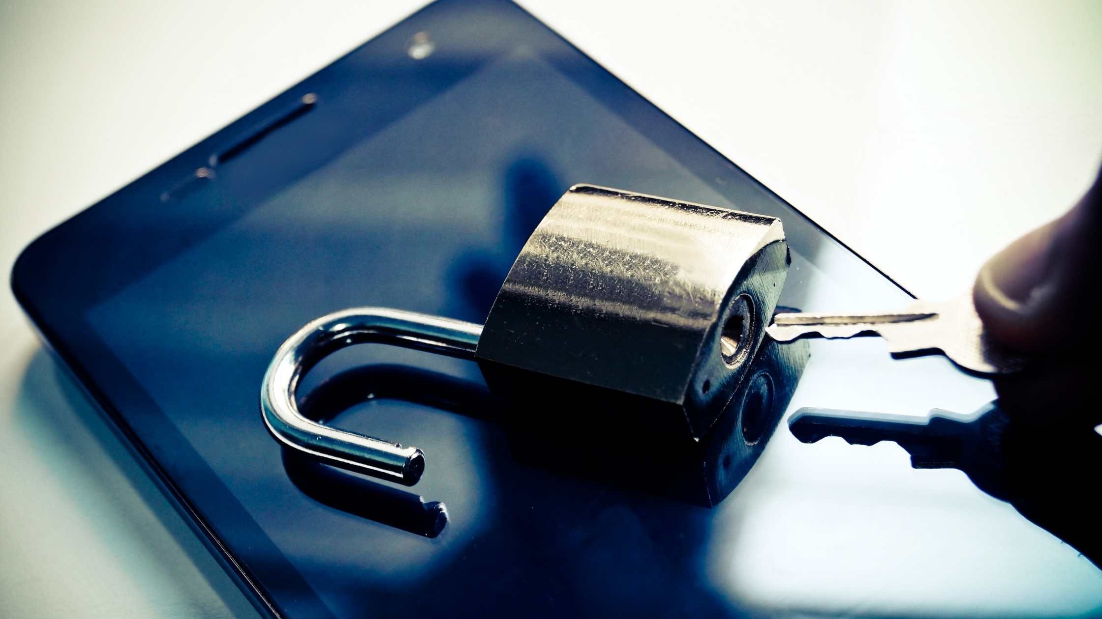 Mobile phone security concept;  Unlocked padlock on top of a mobile phone