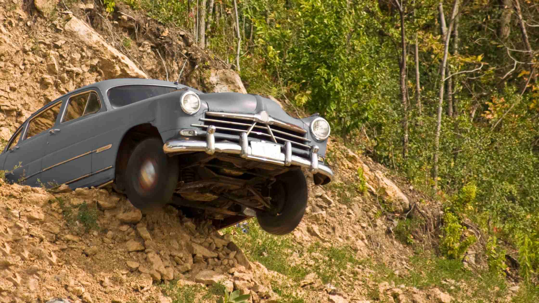 Tipping point concept; vintage car tipping over cliff edge