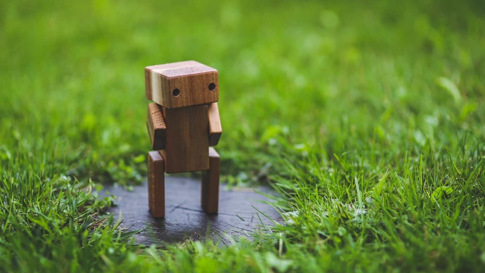 Wooden toy robot surrounded by grass