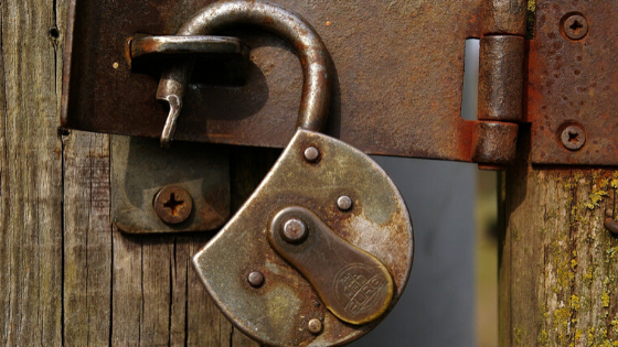 Security concept, rusty unlocked padlock on wooden gate