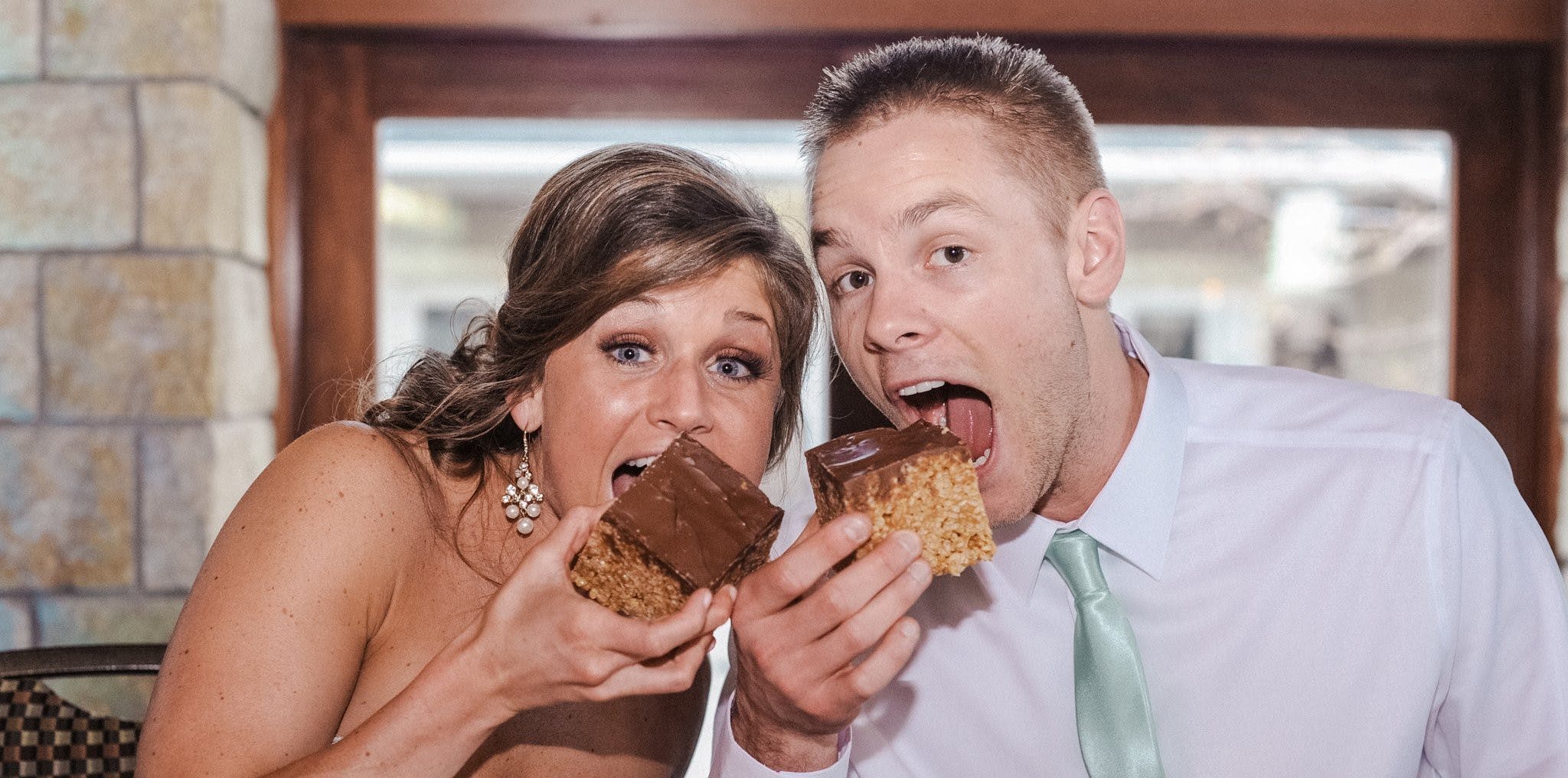 Bride and groom about to bite into chocolate and peanut butter squares
