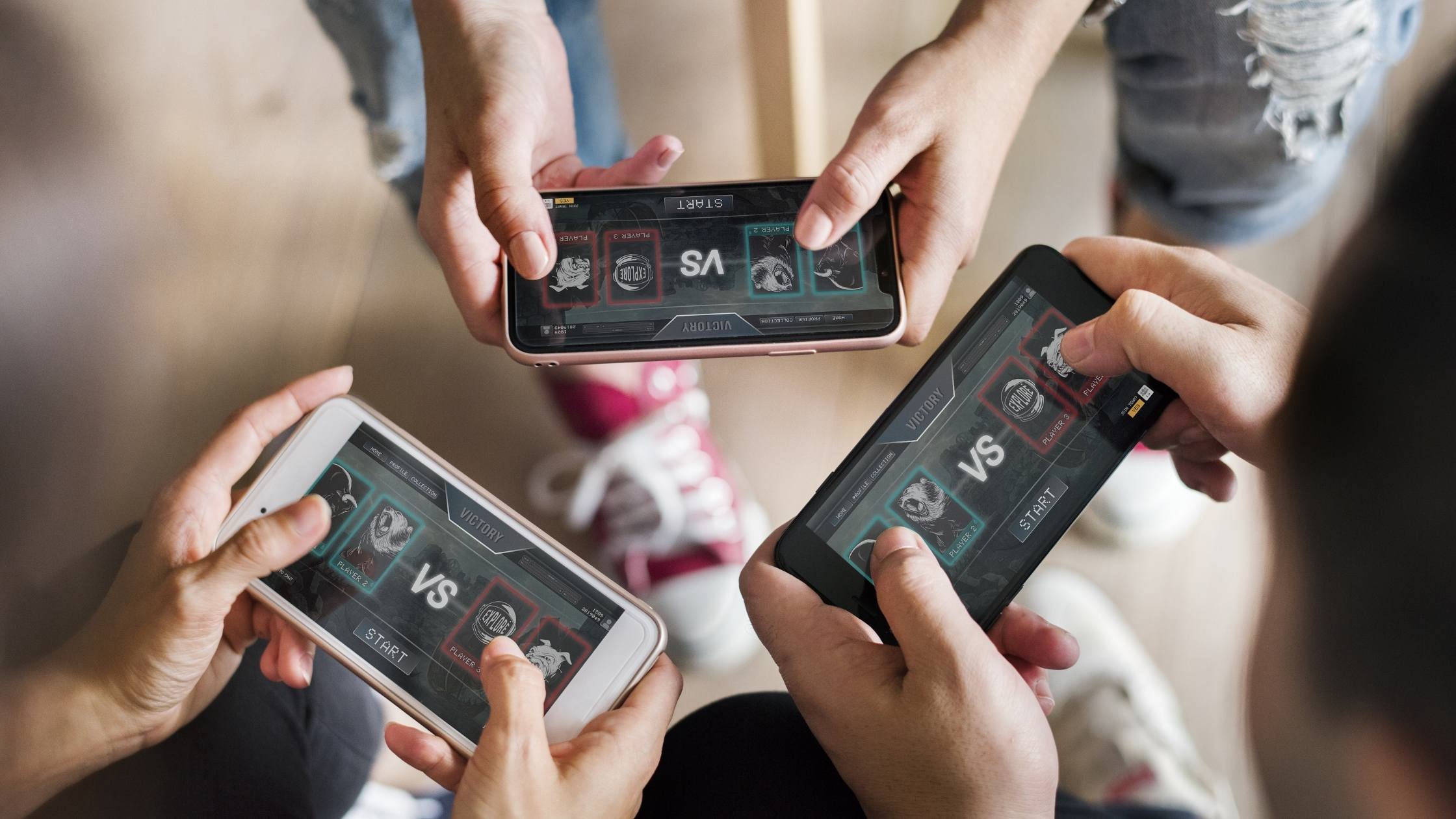 Close up of three people playing a game together on their mobile phones