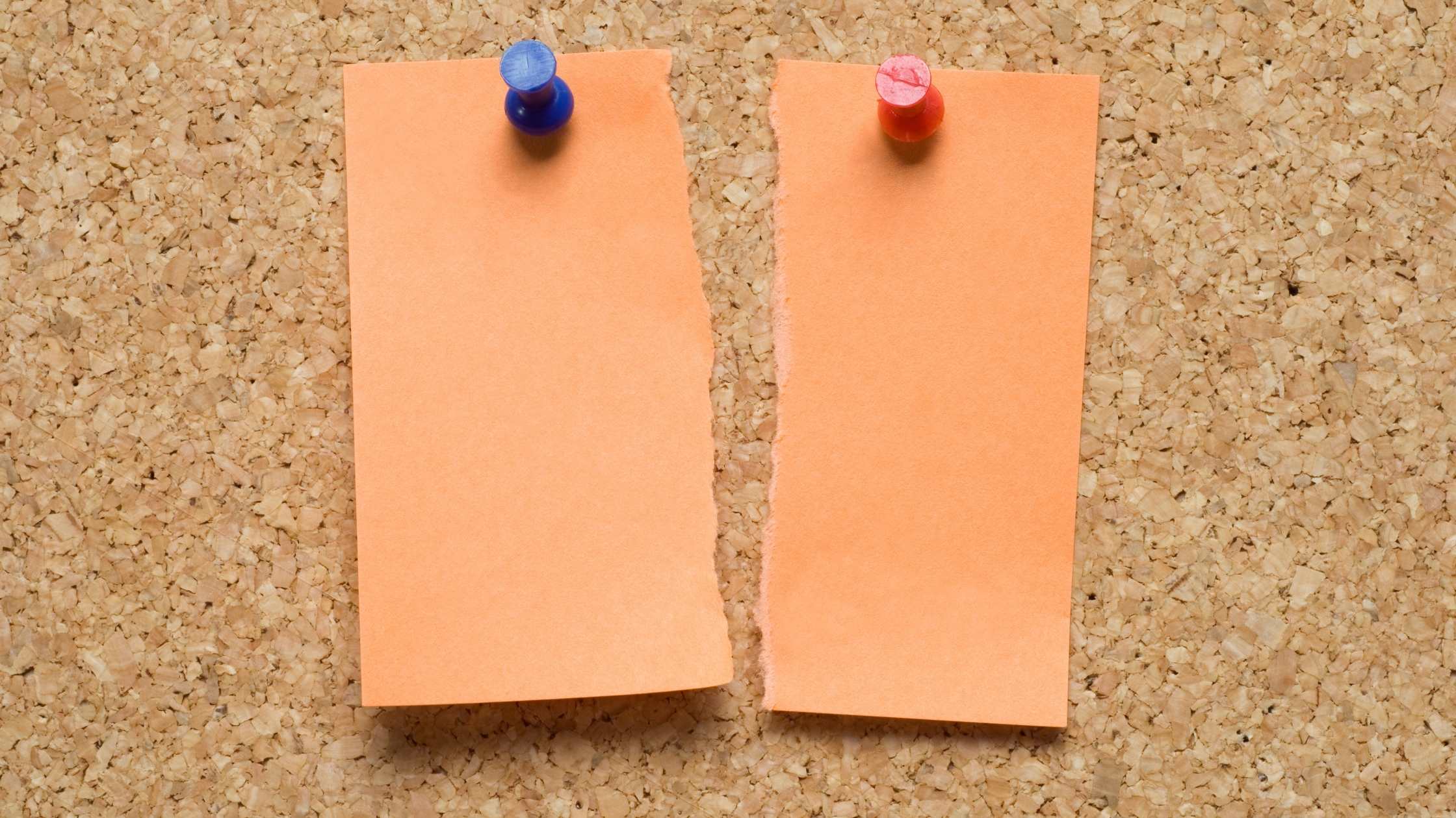 Post-it note torn in two pinned to a cork board