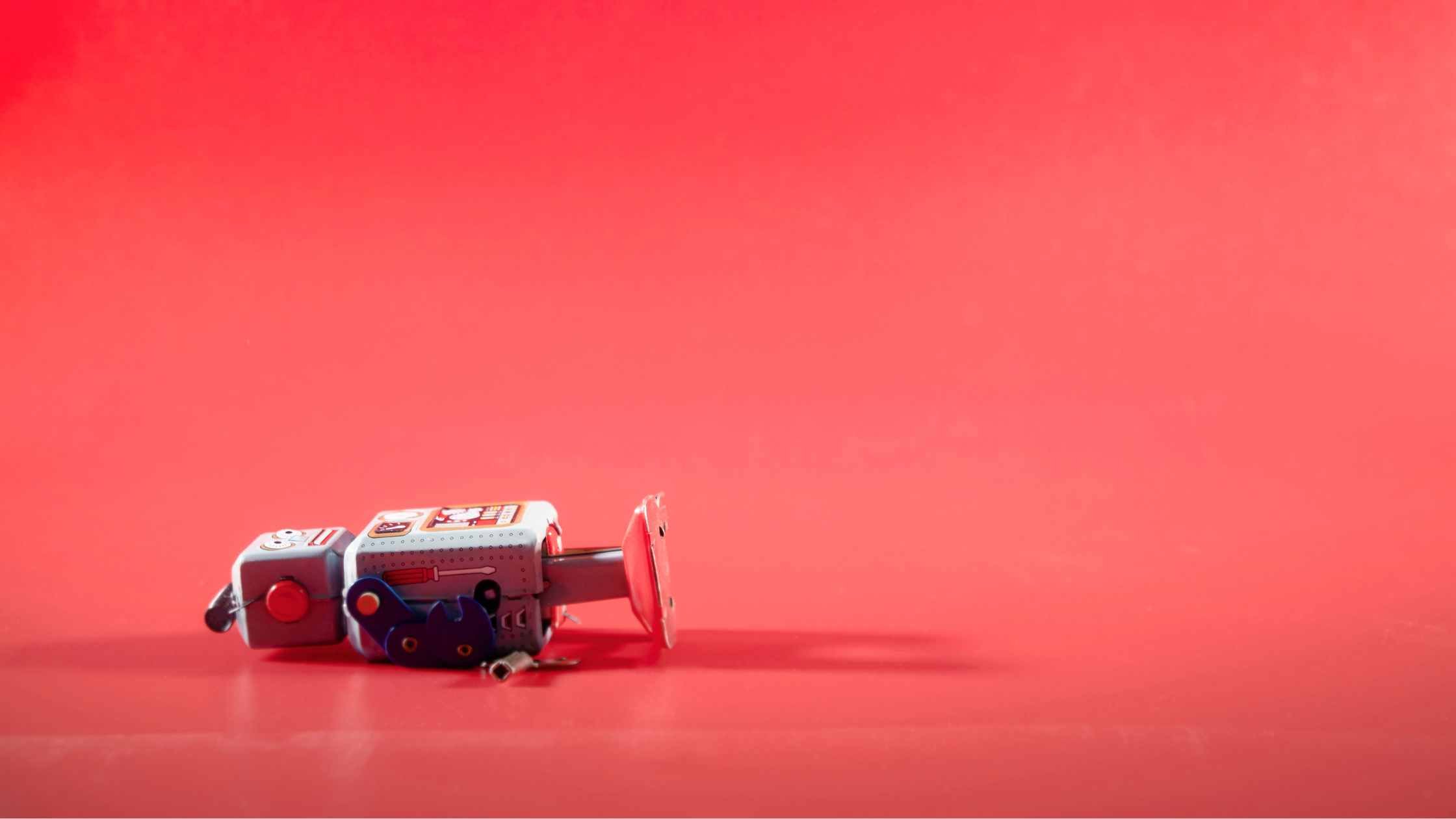 Red toy robot, lying down; red background