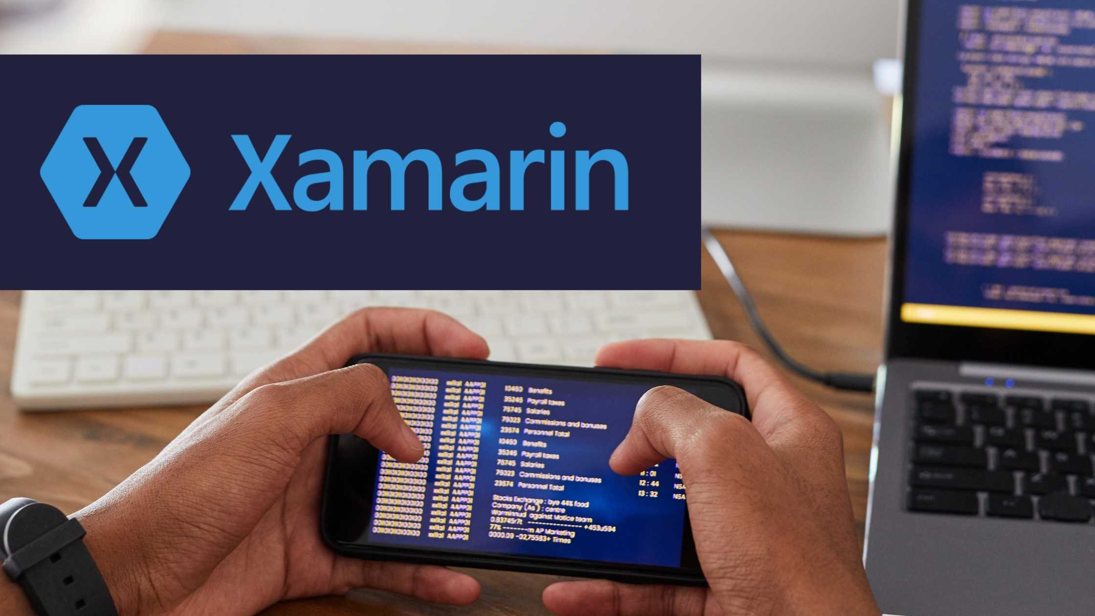 Close up of hands holding mobile phone; laptop and keyboard in background; Dark blue rectangle with Xamarin logo and text